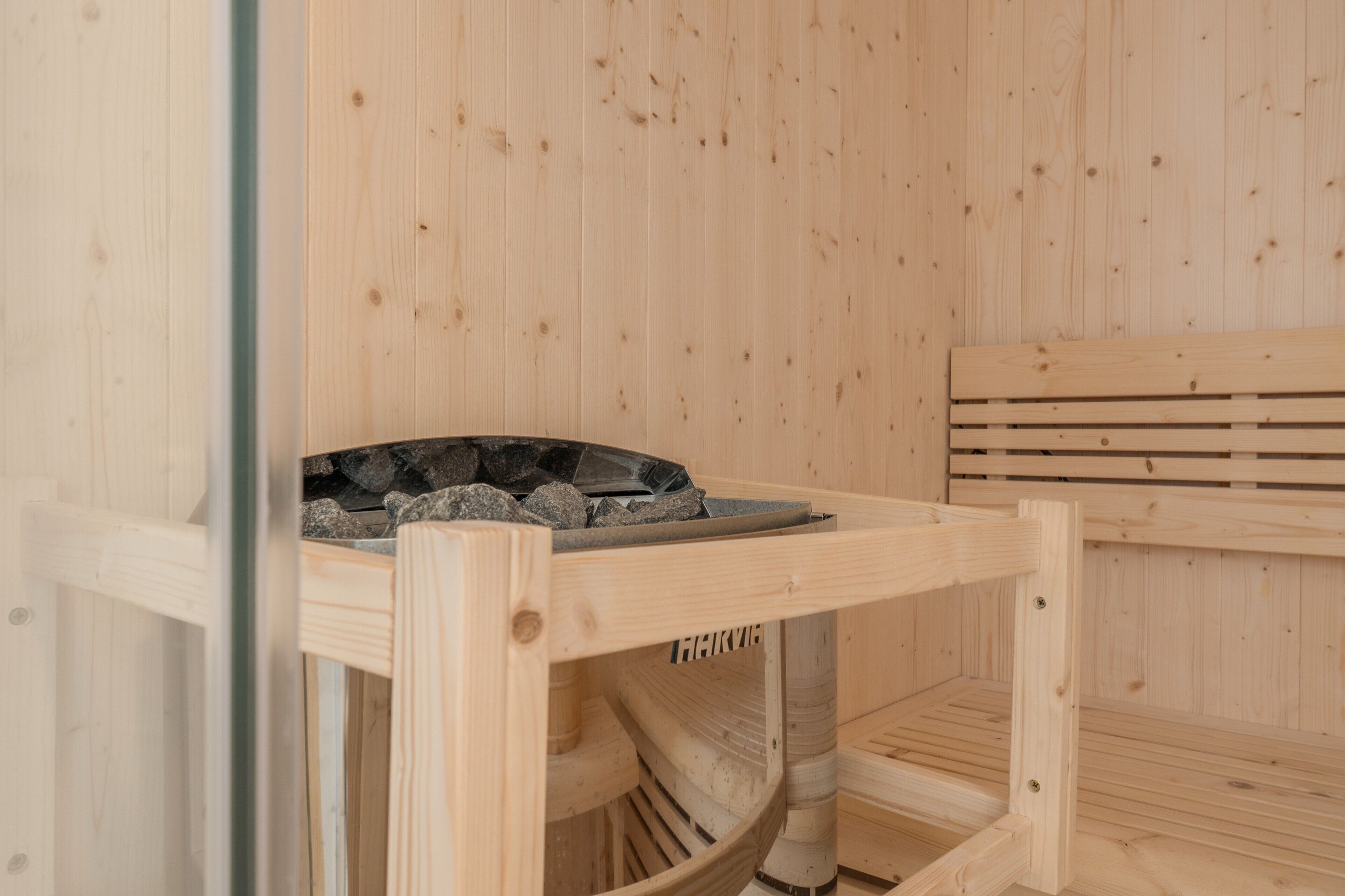 Un sauna avec un banc en bois et un bassin en pierre.