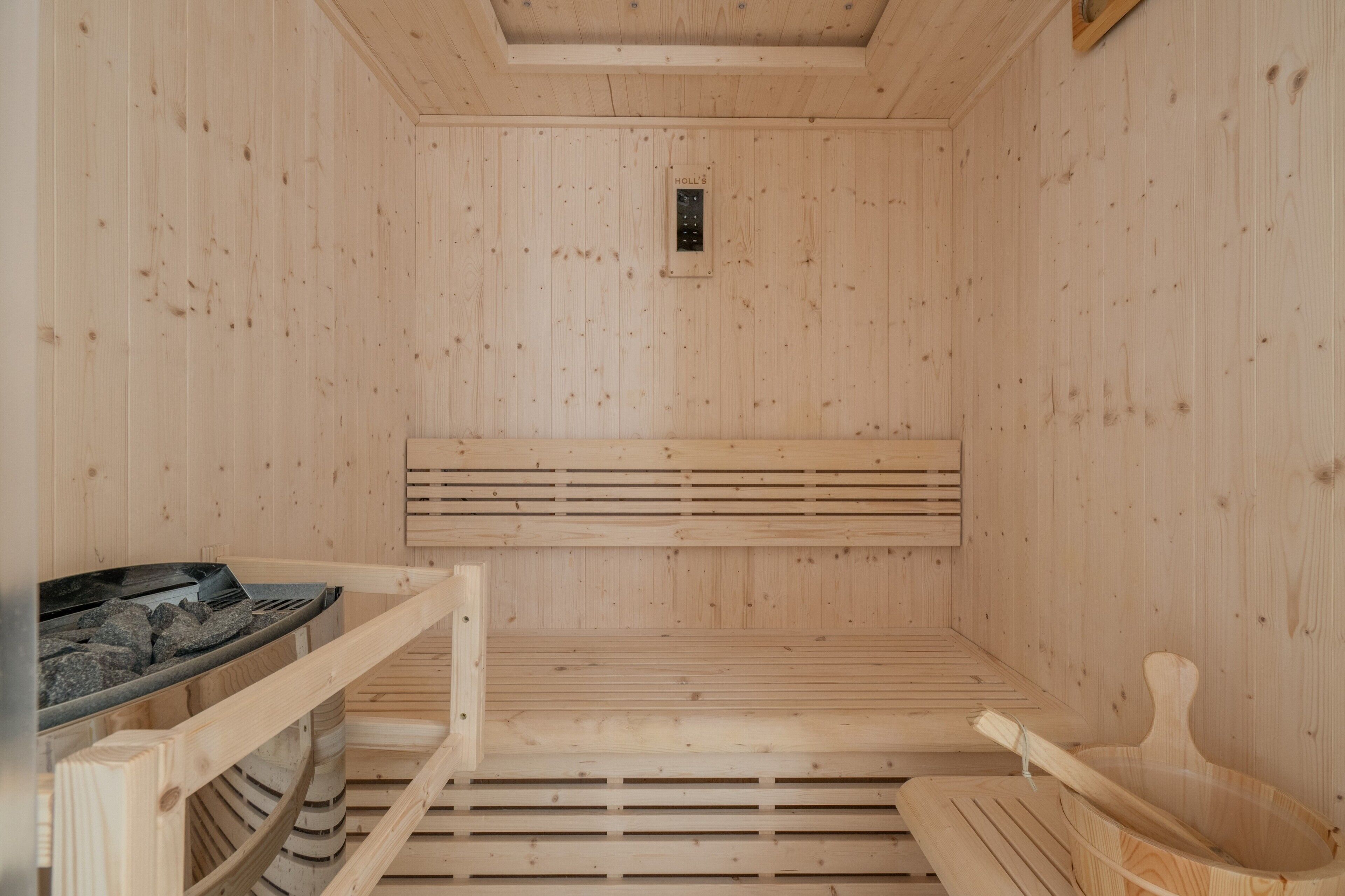 A sauna with wooden walls, a bench, a bench seat, a bench backrest, and a bench leg.