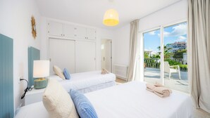 Une chambre d’hôtel avec deux lits, une fenêtre donnant sur un beau paysage, une lampe et une armoire.