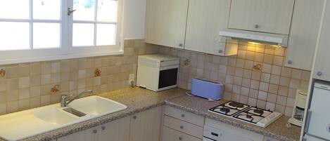 A compact kitchen with a sink, stove, and microwave.