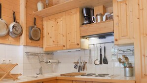 Una cocina con armarios de madera, una estufa y diversos utensilios colgando sobre la encimera.