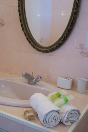 A bathroom with a sink, a mirror, and toiletries. - GITE DE CHARME fleuri à Petit Bourg : Self-catering accommodation (PETIT-BOURG)