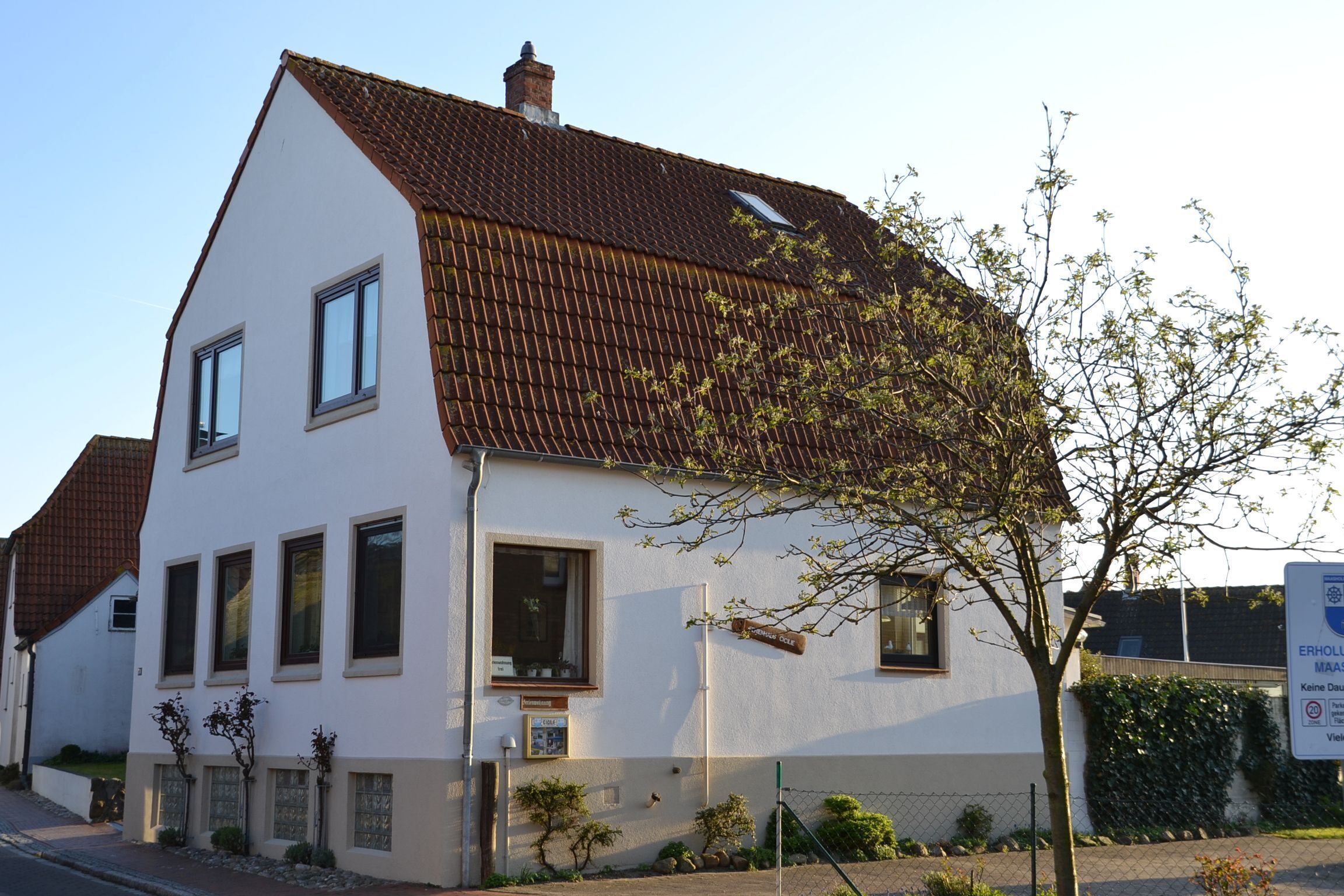 Un bâtiment à deux étages, doté d’un toit en pente, de nombreuses fenêtres et d’un petit arbre devant.