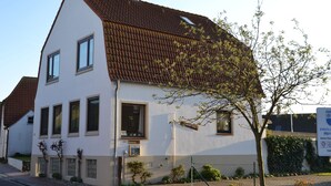 A two-story building with a sloped roof, multiple windows, and a small tree in front. - Apartment on the upper floor - apartment cicilie (Maasholm)