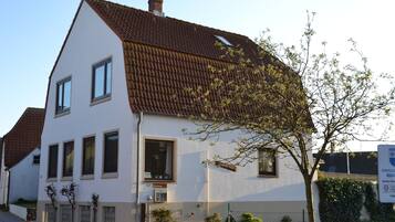 Un bâtiment à deux étages, doté d’un toit en pente, de nombreuses fenêtres et d’un petit arbre devant.