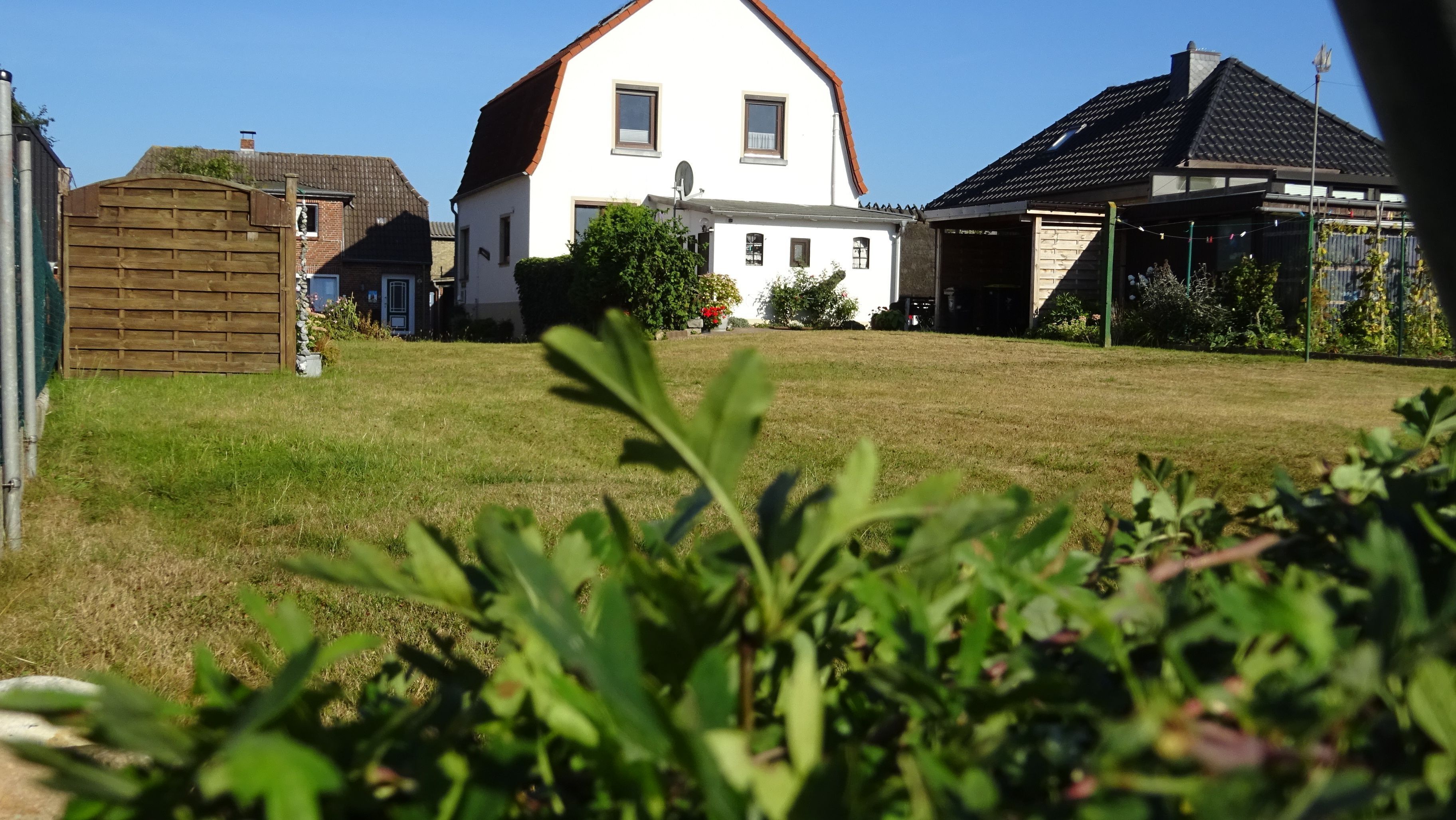 Une maison d’habitation avec un toit en pente, une antenne parabolique bien visible et un garage.