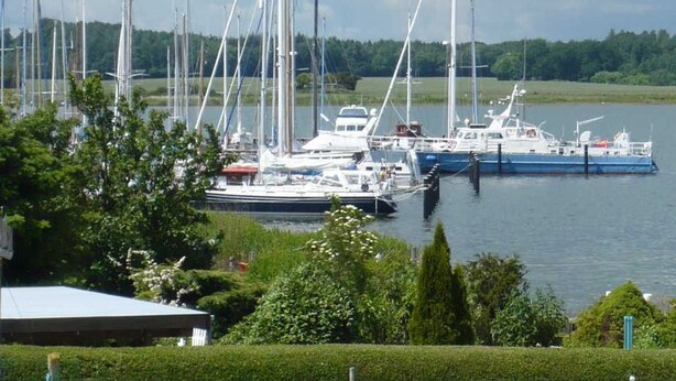 A marina with multiple sailboats docked, surrounded by greenery and a body of water. - Apartment on the upper floor - apartment cicilie (Maasholm)