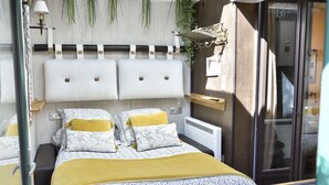 A bedroom with a bed, bedside tables, a nightstand, a mirror, and a window with a view of the outside. - The colonial furnished short-term (Saint-Malo)