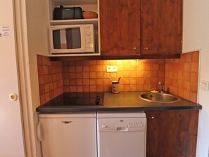 A compact kitchen with a microwave, a sink, and a dishwasher. - Charming 2-Story Duplex, Ski-In, Perfect for Families (Méribel)