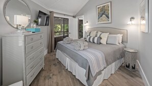 A bedroom with a bed, dresser, and a TV mounted on the wall. - 10 Night Heron | 1 Bedroom Villa | On-site Pool | Walk to Beach | STR #027222 (Hilton Head Island)