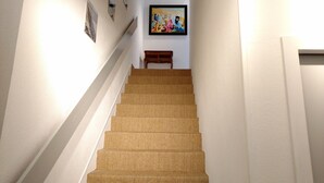 A staircase with a textured carpet, white walls, and a framed painting at the top. - Large and Charming Apartment in Obernai (Obernai)