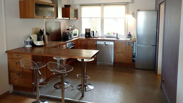 A modern kitchen with wooden cabinets, stainless steel appliances, and a central island with bar stools. - Large and Charming Apartment in Obernai (Obernai)