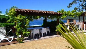 A patio with a pergola, white chairs, and a table overlooking the sea. - Waterfront self-catered house  (Coti-Chiavari)