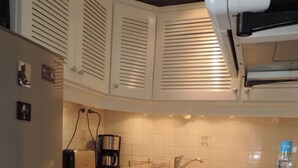 A kitchen with white cabinets, a coffee maker, a toaster, and a blue water dispenser on the counter.