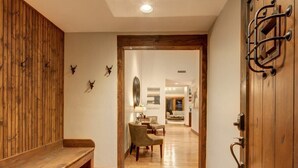 A hallway with a wooden bench, a door with a metal handle, and a wall with mounted animal horns.