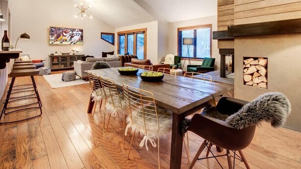 A spacious living area with a wooden dining table, chairs, and a fireplace.
