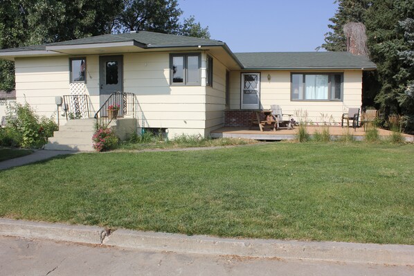 A single-story house with a front porch, a small garden, and a clear sky. - Family Friendly Cozy Farmhouse (Fort Shaw)
