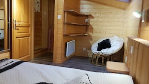 Ein Zimmer in einer Holzhütte mit einem Bett, einem Sessel und einem kleinen Tisch.