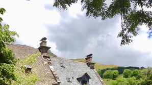 A stone house with a tiled roof, a small garden, and a play area with a slide and swings. - 4* TYPICAL HOUSE IN BARRIADE 4 pers (Mandailles)