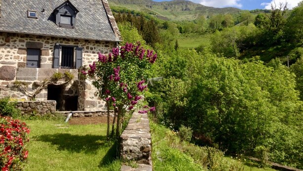 A stone house with a sloped roof, a chimney, and a small porch. - 4* TYPICAL HOUSE IN BARRIADE 4 pers (Mandailles)