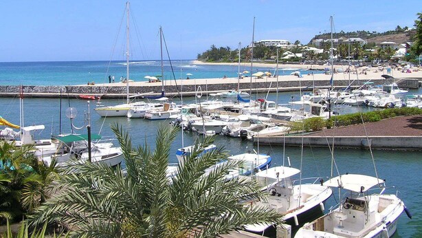 A marina with multiple boats docked, a pier extending into the water, and a beach area with umbrellas. - Escale Chic!  Charming villa in Saint-Gilles-Les-Bains (Saint-Gilles les Bains)