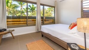 A bedroom with a large window, a bed, a bedside table, and a lamp. - Escale Chic!  Charming villa in Saint-Gilles-Les-Bains (Saint-Gilles les Bains)