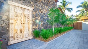 A stone wall with a decorative wooden door, a paved walkway, and green plants. - Escale Chic!  Charming villa in Saint-Gilles-Les-Bains (Saint-Gilles les Bains)