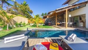 A modern house with a swimming pool, outdoor furniture, and a stone wall. - Escale Chic!  Charming villa in Saint-Gilles-Les-Bains (Saint-Gilles les Bains)