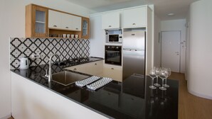 Una cocina moderna con encimera negra, electrodomésticos de acero inoxidable y un salpicadero decorativo.