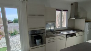 A modern kitchen with white cabinets, a built-in oven, a sink, and a window with curtains.