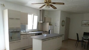 A modern kitchen with white cabinetry, a central island, and a ceiling fan.