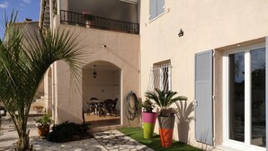 A two-story building with a stone patio, outdoor seating area, and potted plants.