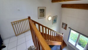 A wooden staircase with a handrail, white tiled floor, and a window with a view of greenery. - Duplex Apartment 65m2 in quiet residence in Uzès, free Parking, garage in Option (Uzès)