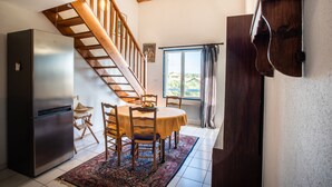 A kitchen with a wooden staircase, a dining table with chairs, a refrigerator, and a window with curtains. - Duplex Apartment 65m2 in quiet residence in Uzès, free Parking, garage in Option (Uzès)