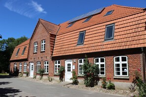 Een gebouw van rode baksteen met veel ramen en een schuin dak.