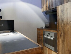 A compact kitchen with a built-in oven, a toaster, and a sink.