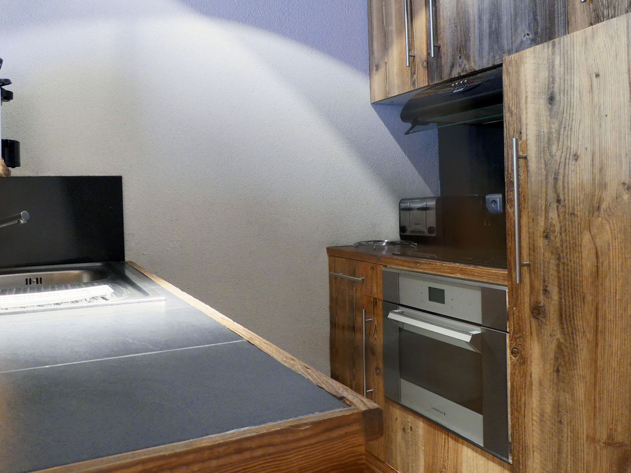 Una cocina compacta con horno integrado, tostadora y pileta.
