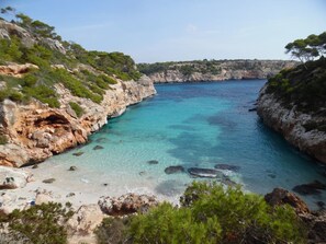 Un paisaje costero con acantilados rocosos, aguas turquesas cristalinas y vegetación escasa.
