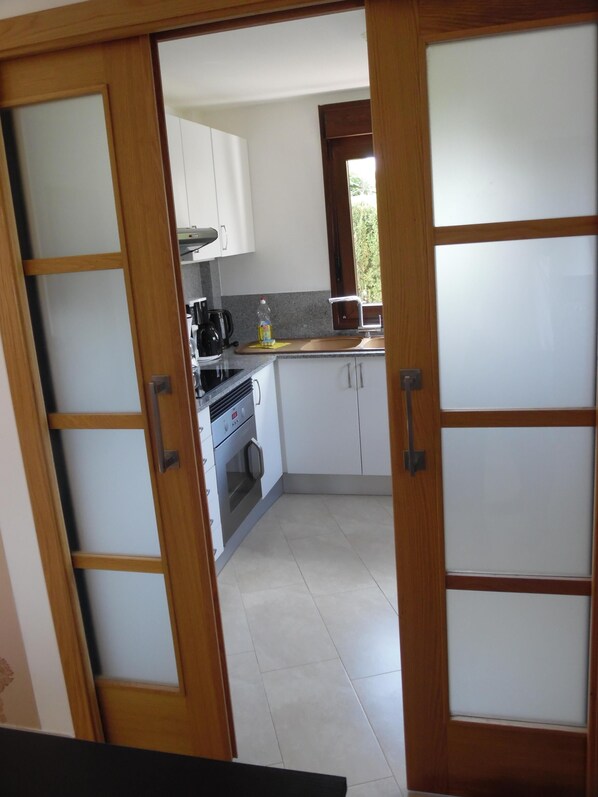 Una cocina compacta con armarios blancos, una estufa y un lavabo.
