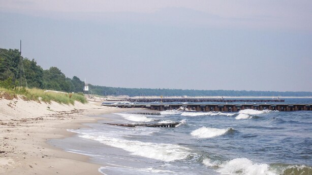 A beach with a pier extending into the water, sandy dunes, and a lighthouse in the background. - 1 bedroom awesome apartment in Glemmingebro (Glemmingebro)