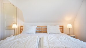A bedroom with a wooden headboard, two bedside lamps, and a bed with white bedding. - 1 bedroom awesome apartment in Glemmingebro (Glemmingebro)