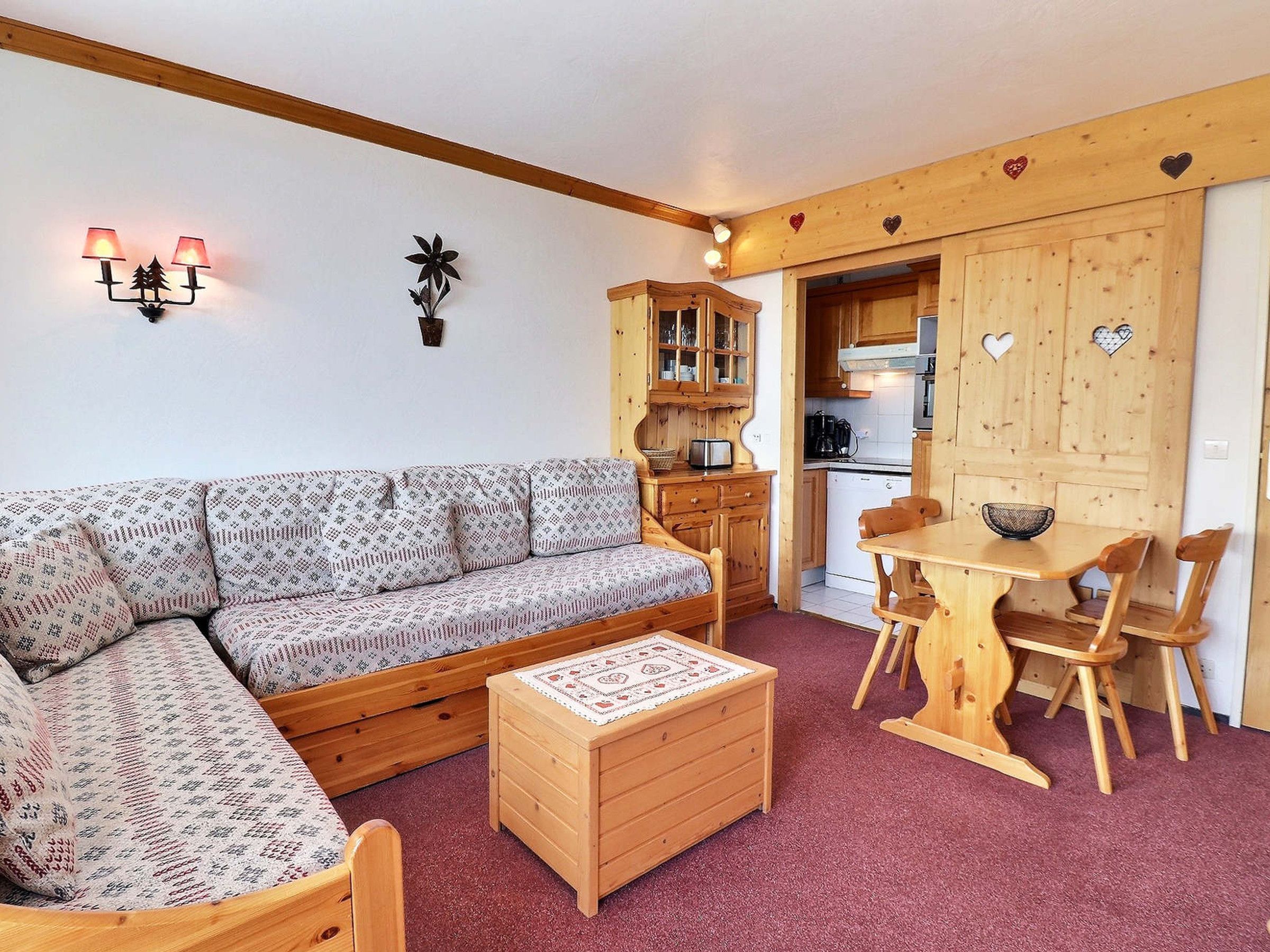 Ein gemütliches Wohnzimmer mit einem gemusterten Sofa, einem Holztisch und einem Essbereich mit Tisch und Stühlen.