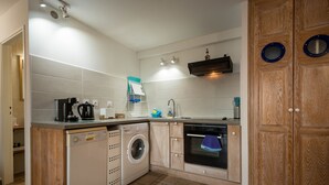A compact kitchen with a washing machine, oven, and a sink. - REVE AUSTRAL T2 C au bord du Lagon 180° sea view (St Pierre)