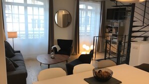 A modern living room with a sofa, a dining table, and a TV. - DUPLEX IN BEAUTIFUL TOUQUETTOISE, PROX. SHOPS & ST. JEAN STREET, 150M SEA FRONT (Le Touquet-Paris-Plage)