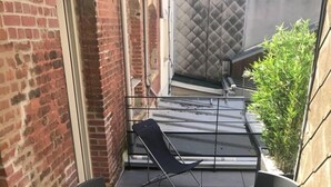 A small outdoor patio with two black chairs and a table, brick walls, and a metal railing. - DUPLEX IN BEAUTIFUL TOUQUETTOISE, PROX. SHOPS & ST. JEAN STREET, 150M SEA FRONT (Le Touquet-Paris-Plage)