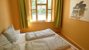 Une chambre avec un lit, des rideaux verts et une fenêtre donnant sur un paysage verdoyant.