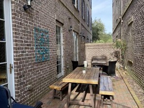 A brick building with a wooden table and benches, a metal gate, and a brick wall with a metal gate.