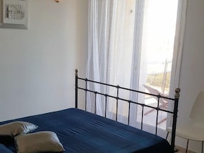 A bedroom with a bed, a chair, and a window with curtains. - Appartment 55m² with sea view terrace 200m Calvi b (Calvi)