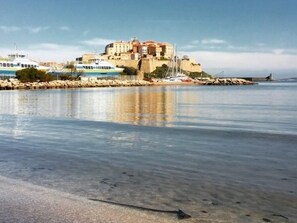 A coastal view with a historic building, boats, and a calm sea.