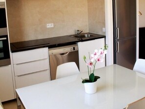 A modern kitchen with a dishwasher, sink, and stainless steel refrigerator. There is a white table with a potted orchid. - Appartment 55m² with sea view terrace 200m Calvi b (Calvi)